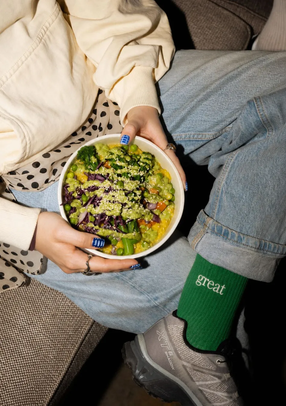 Un bol de salade Great posé sur les genoux, chaussettes vertes brodées great